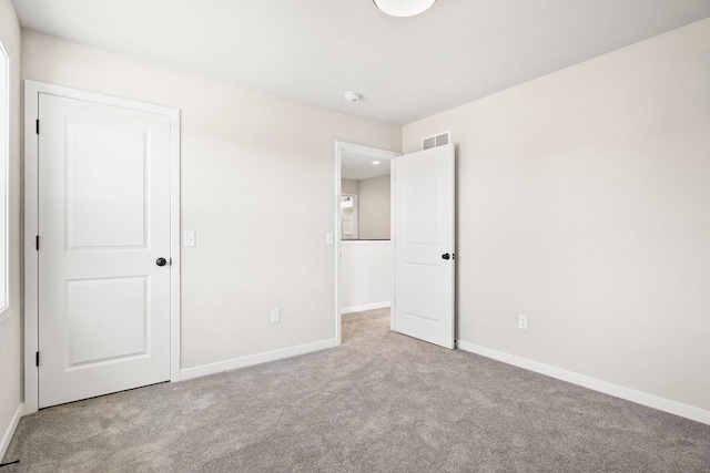 unfurnished bedroom with carpet flooring, baseboards, and visible vents