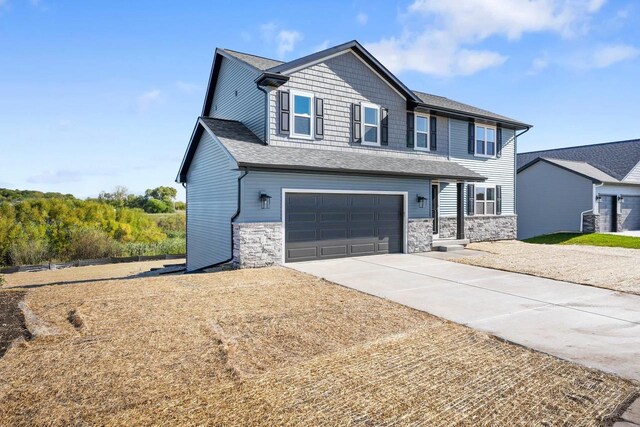 craftsman-style home featuring concrete driveway, an attached garage, stone siding, and a shingled roof