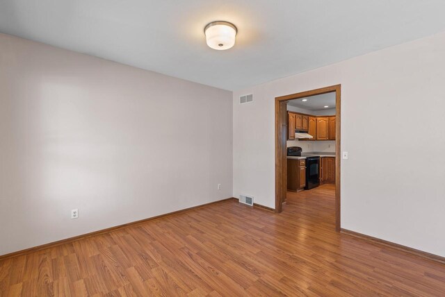 unfurnished room with baseboards, light wood finished floors, and visible vents