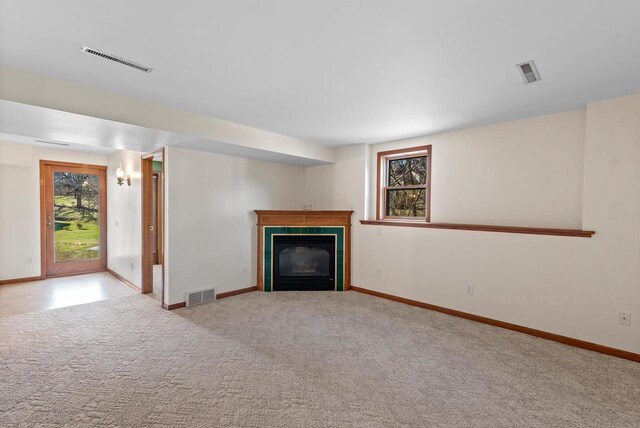 unfurnished living room featuring carpet flooring, visible vents, and a tiled fireplace