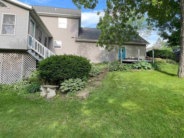 rear view of house featuring a lawn, a shingled roof, and a deck