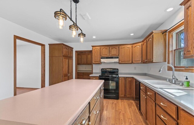 kitchen featuring light countertops, under cabinet range hood, a sink, and black appliances
