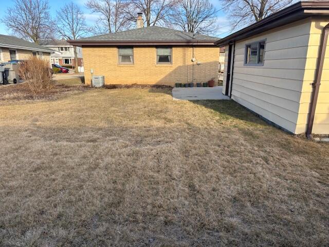 rear view of property with a yard, brick siding, and cooling unit