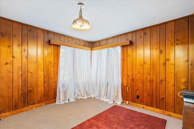 carpeted spare room featuring wooden walls