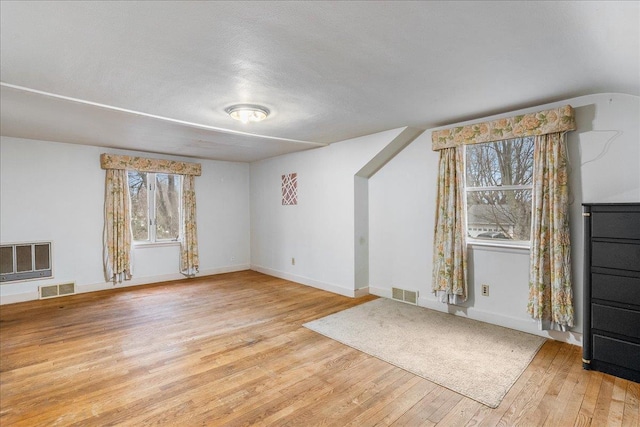 unfurnished living room with heating unit, baseboards, visible vents, and light wood finished floors