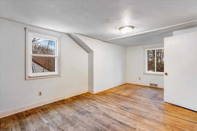 bonus room with visible vents, plenty of natural light, baseboards, and wood-type flooring