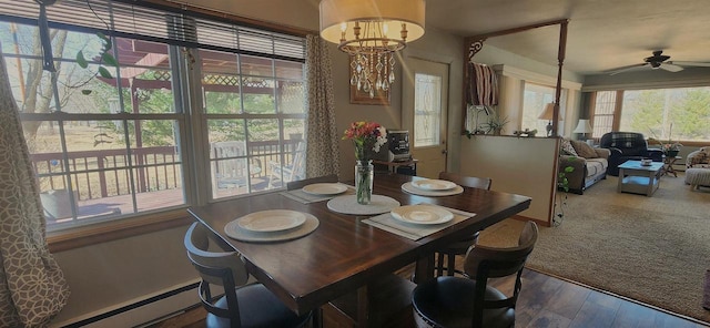 dining space featuring baseboard heating, wood finished floors, and ceiling fan with notable chandelier