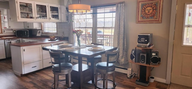 dining area with dark wood finished floors, plenty of natural light, a baseboard heating unit, and baseboards