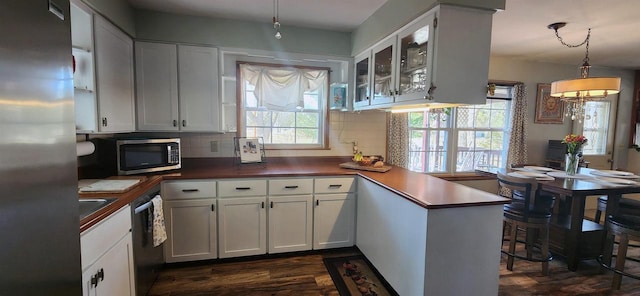 kitchen featuring white cabinetry, a peninsula, dark wood-style floors, and stainless steel appliances