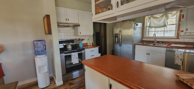 kitchen with under cabinet range hood, a sink, stainless steel appliances, white cabinets, and decorative backsplash