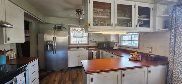 kitchen featuring a peninsula, a sink, decorative backsplash, white cabinets, and appliances with stainless steel finishes