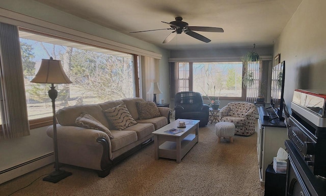 carpeted living area featuring baseboard heating, a healthy amount of sunlight, and a ceiling fan