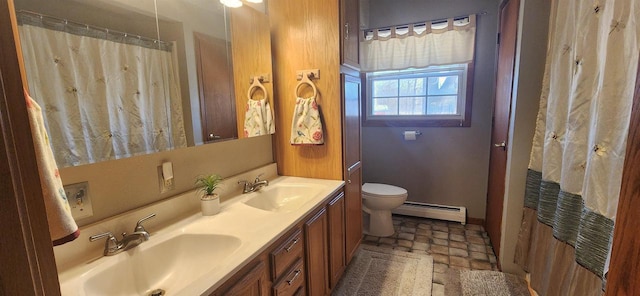 bathroom featuring double vanity, baseboard heating, toilet, and a sink