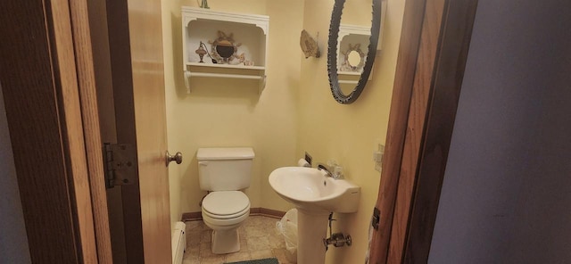 half bath featuring tile patterned flooring, toilet, baseboards, and a sink