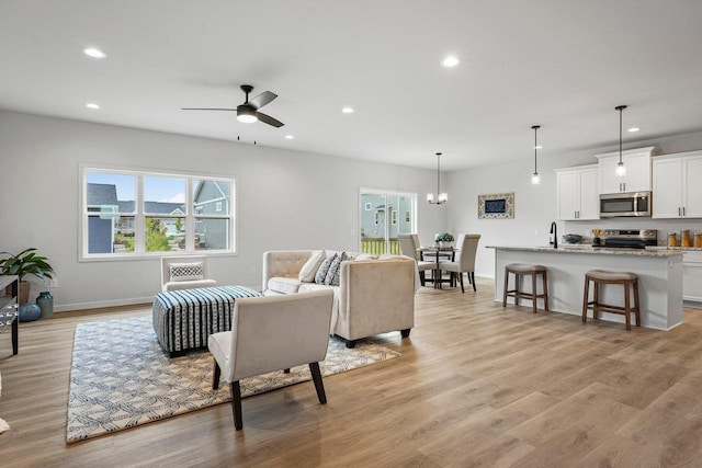 living area with recessed lighting, light wood-style flooring, baseboards, and ceiling fan