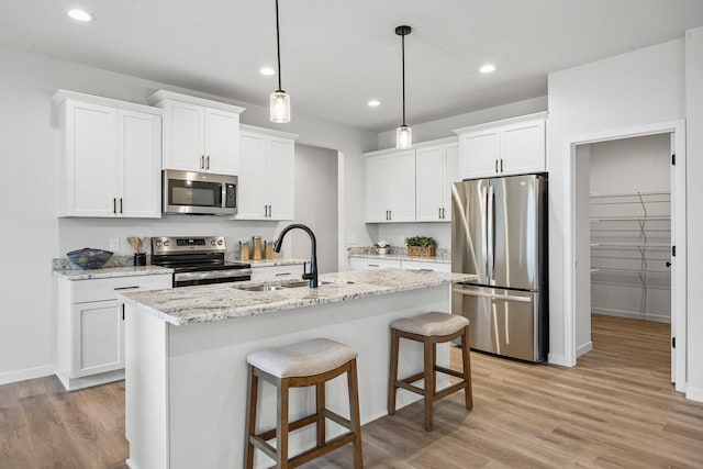 kitchen featuring a sink, light wood-style floors, appliances with stainless steel finishes, and white cabinets