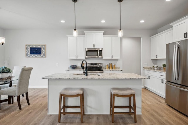 kitchen featuring a kitchen island with sink, appliances with stainless steel finishes, a kitchen bar, and a sink