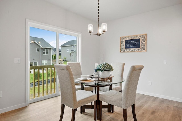 dining area with light wood finished floors, an inviting chandelier, and baseboards