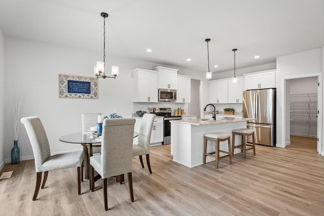 dining room featuring recessed lighting, light wood-style floors, baseboards, and a chandelier