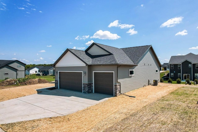 view of side of property featuring driveway, roof with shingles, an attached garage, central AC, and a residential view