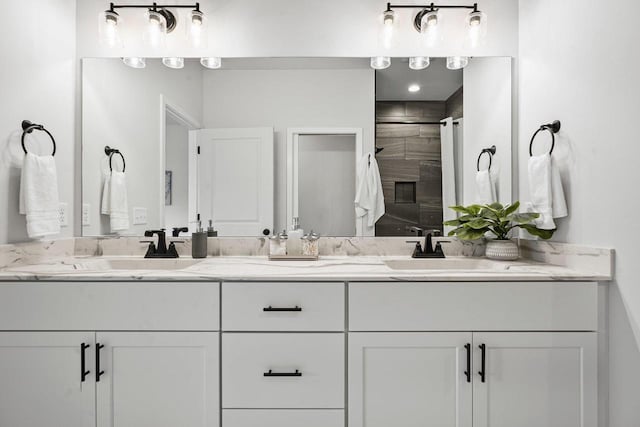 full bathroom featuring a sink, double vanity, and a tile shower