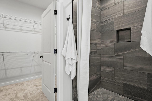 bathroom with a walk in closet and tiled shower