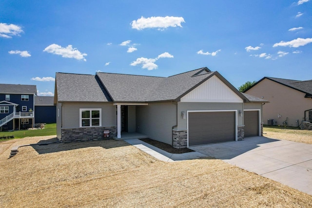 view of front of home with stone siding, driveway, a garage, and roof with shingles