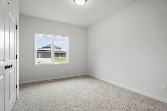 carpeted spare room featuring baseboards