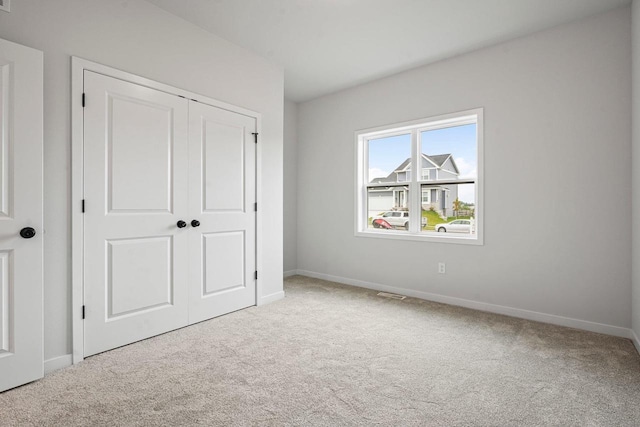 unfurnished bedroom with visible vents, baseboards, a closet, and carpet floors