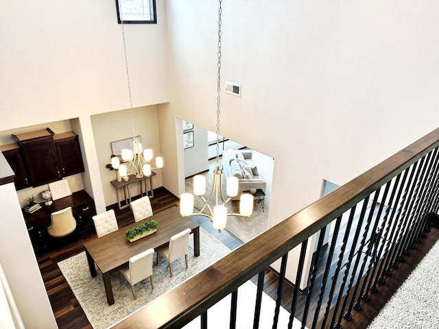 interior space featuring stairway, wood finished floors, visible vents, a towering ceiling, and a notable chandelier