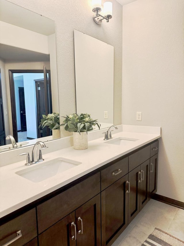 full bathroom with double vanity, baseboards, and a sink