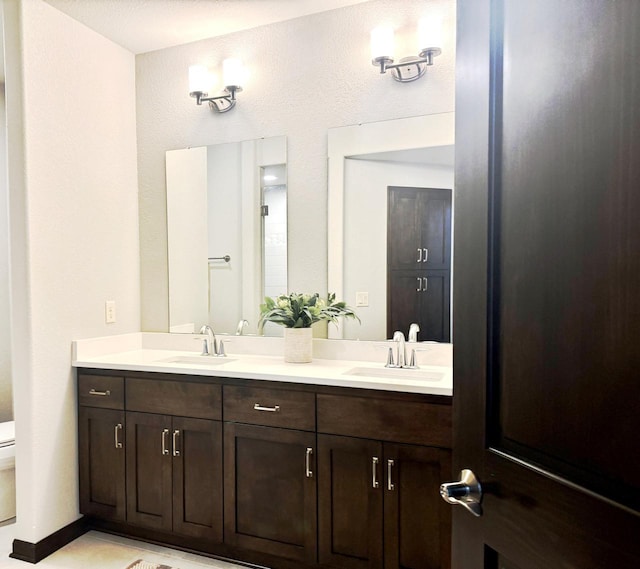 full bathroom with a sink, toilet, and double vanity