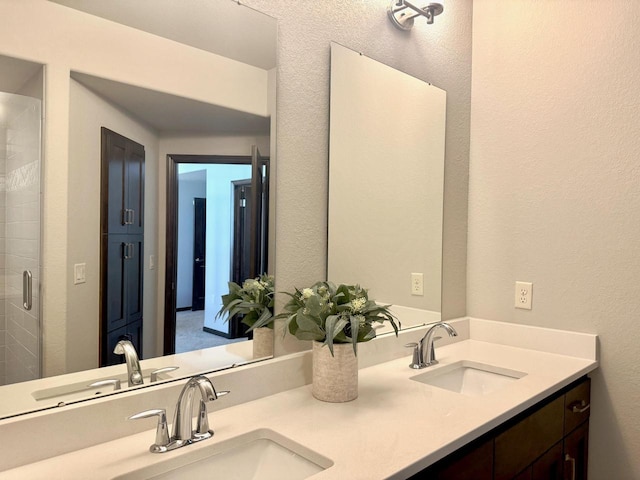 bathroom featuring a sink, tiled shower, and double vanity