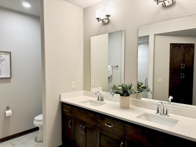 full bathroom with a sink, toilet, and double vanity