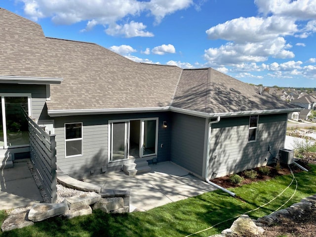 rear view of property with entry steps, roof with shingles, and a patio