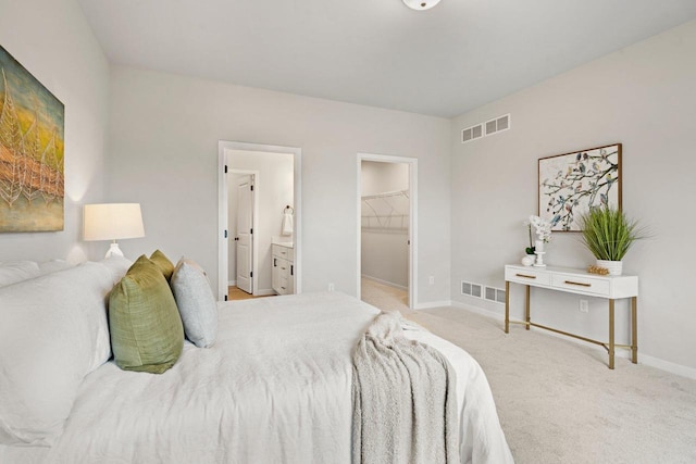 bedroom featuring a spacious closet, baseboards, visible vents, and carpet floors