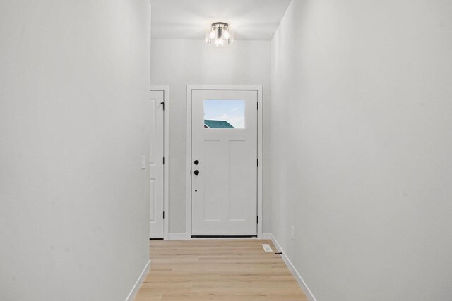 entryway featuring an inviting chandelier, light wood-style flooring, and baseboards