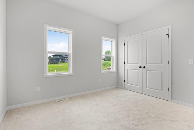 unfurnished bedroom with visible vents, baseboards, carpet, and a closet