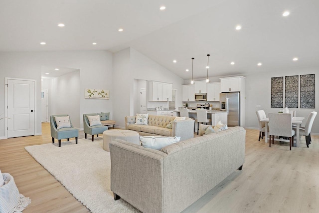 living room with recessed lighting, light wood-type flooring, and high vaulted ceiling