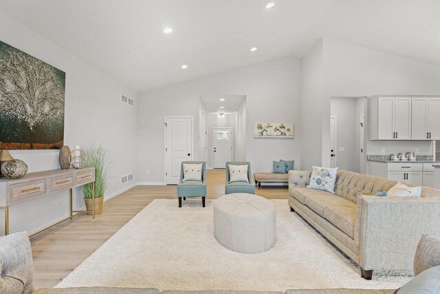 living room with vaulted ceiling, recessed lighting, light wood-type flooring, and visible vents