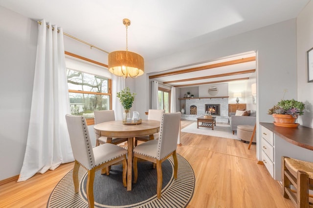 dining room with a brick fireplace, light wood finished floors, and a chandelier