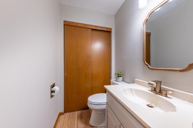 half bath with vanity, toilet, and wood finished floors