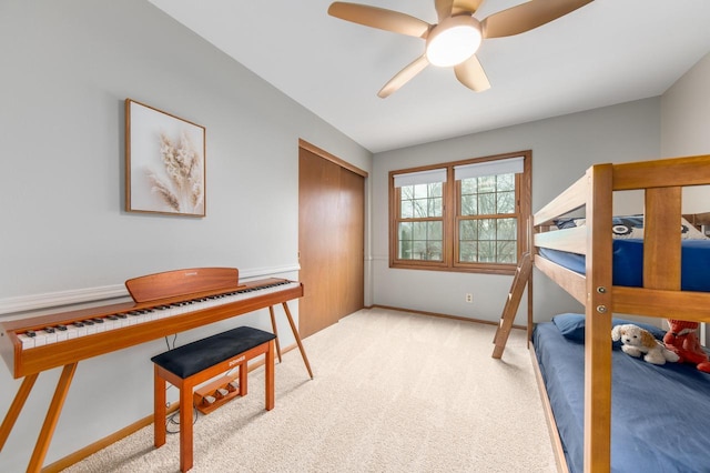 bedroom featuring ceiling fan, light colored carpet, a closet, and baseboards