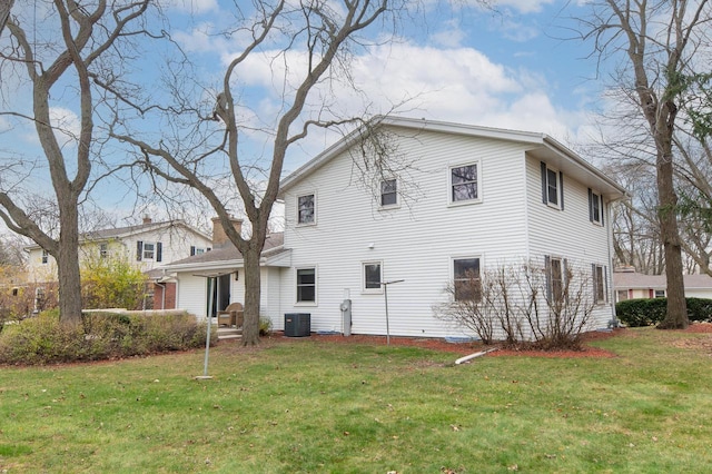 rear view of property featuring a lawn and central AC