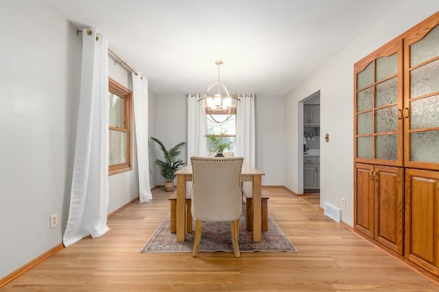 dining space with visible vents, baseboards, light wood-style flooring, and a chandelier