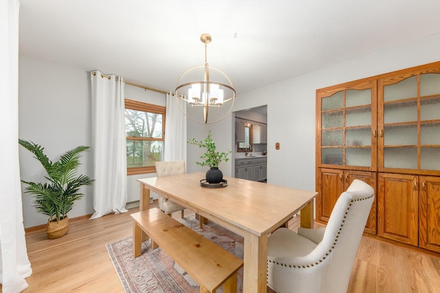 dining space with baseboards, an inviting chandelier, and light wood-style flooring