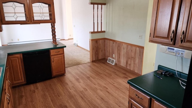 kitchen with visible vents, light wood finished floors, black dishwasher, wainscoting, and dark countertops