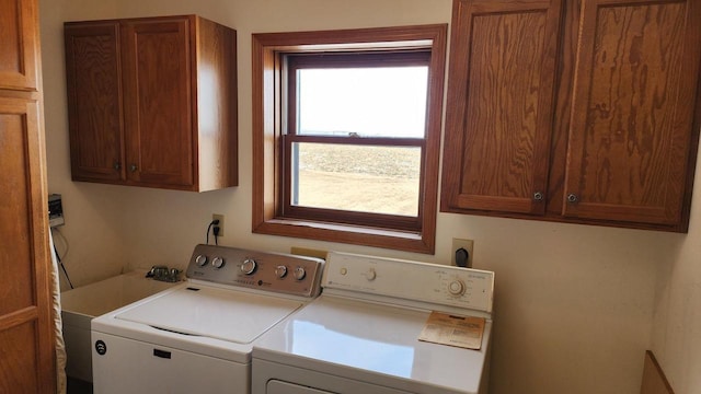 clothes washing area with washer and dryer and cabinet space