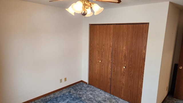 unfurnished bedroom with a closet, dark carpet, a ceiling fan, and baseboards