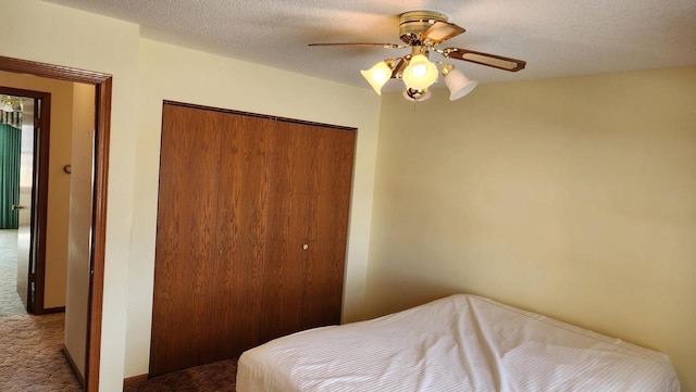 carpeted bedroom with a closet, a textured ceiling, and a ceiling fan